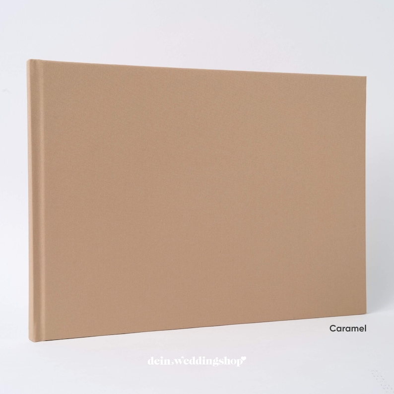 May include: A caramel-colored photo album with a fabric cover. The album is rectangular and closed, with a spine on the left side. The word "Caramel" is printed on the bottom right corner.