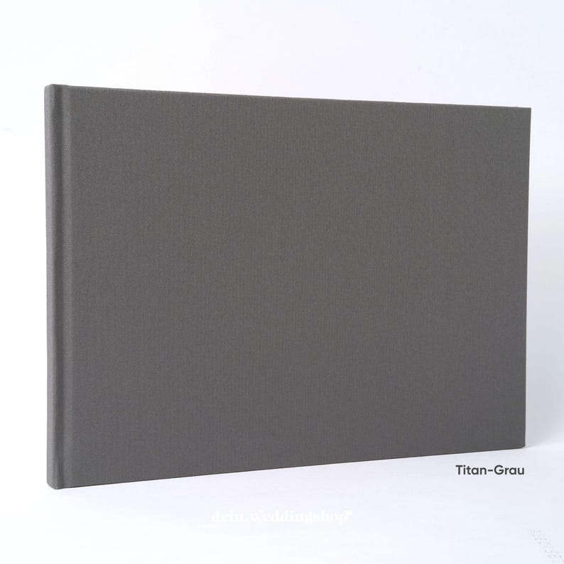 May include: A rectangular, gray photo album with a textured cover. The album is closed and has a spine on the left side. The text "Titan-Grau" is visible in the lower right corner.