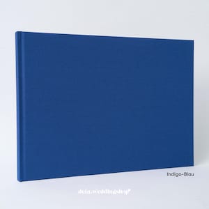 May include: A rectangular indigo blue book with a textured cover. The book is closed and has a spine on the left side. The text "Indigo-Blau" is in the lower right corner. The website "dein.weddingshop" is in the lower left corner.