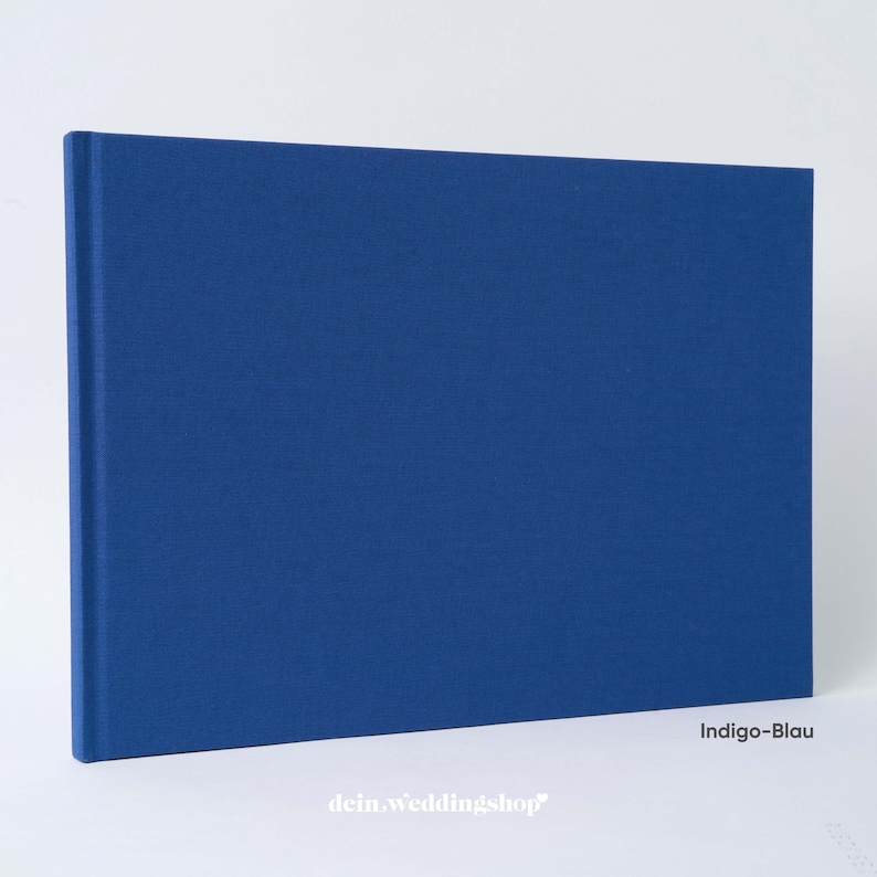 May include: A rectangular indigo blue book with a textured cover. The book is closed and has a spine on the left side. The text "Indigo-Blau" is in the lower right corner. The website "dein.weddingshop" is in the lower left corner.