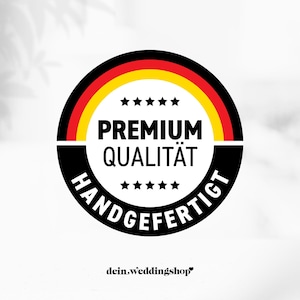 May include: A circular emblem with the German flag colors, black, red, and yellow. The words "PREMIUM QUALIT&Auml;T" and "HANDGEFERTIGT" are in white text. The emblem also includes the text "dein.weddingshop".