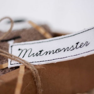 May include: A brown fabric gift box with a white label that says "Nutmonster" in black embroidery.