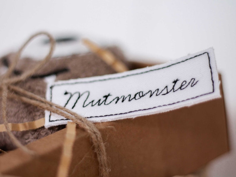 May include: A brown fabric gift box with a white label that says "Nutmonster" in black embroidery.