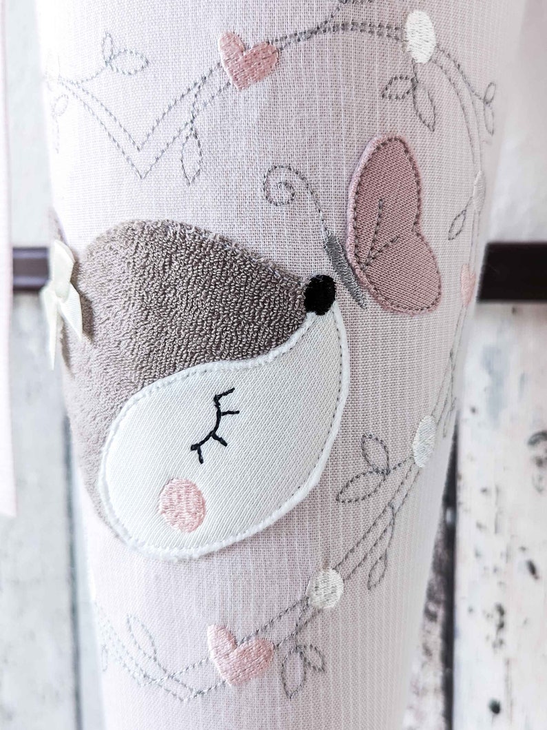 May include: Pink and gray embroidered tights with a cute little mouse design. The mouse has a pink nose and a closed eye. The tights are decorated with a butterfly and hearts.