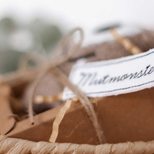May include: A brown cardboard box with a white fabric tag that says "Mintmonster" tied with twine. The box is sitting in a woven basket.