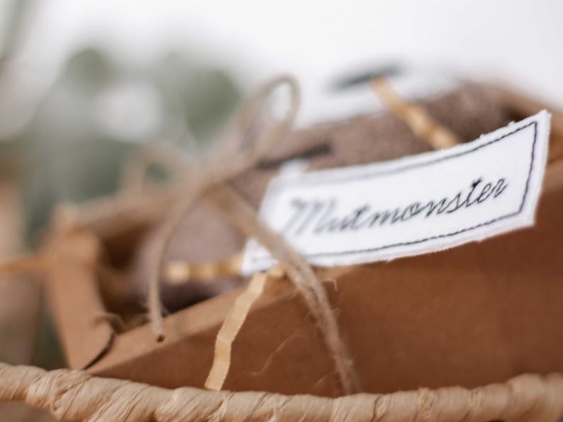 May include: A brown cardboard box with a white fabric tag that says "Mintmonster" tied with twine. The box is sitting in a woven basket.