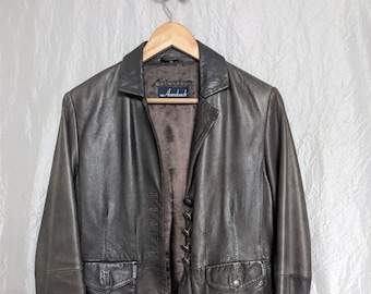 Könnte beinhalten: Eine braune Lederjacke mit Knopfleiste und zwei Taschen. Die Jacke hat ein Etikett mit der Aufschrift "Avancé".