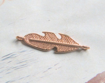 May include: A gold-toned feather charm with a detailed design. The charm has two loops on either end for attaching to jewelry.