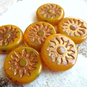 May include: Six round, amber glass beads with a gold sun design. The beads are approximately 1 inch in diameter.