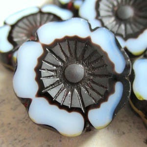 Könnte beinhalten: Nahaufnahme einer Glasblumenperle mit einem schwarz-weißen Design. Die Perle hat ein erhabenes Sternmuster in der Mitte.