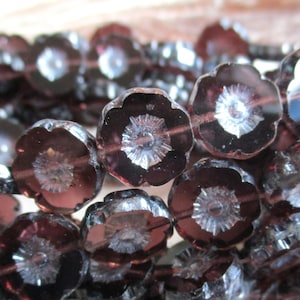 Può includere: Primo piano di una collana di perline a forma di fiore viola scuro. Ogni perlina ha un centro dettagliato color argento ed è infilata insieme. Le perline sono di vetro e sono ideali per la creazione di gioielli.