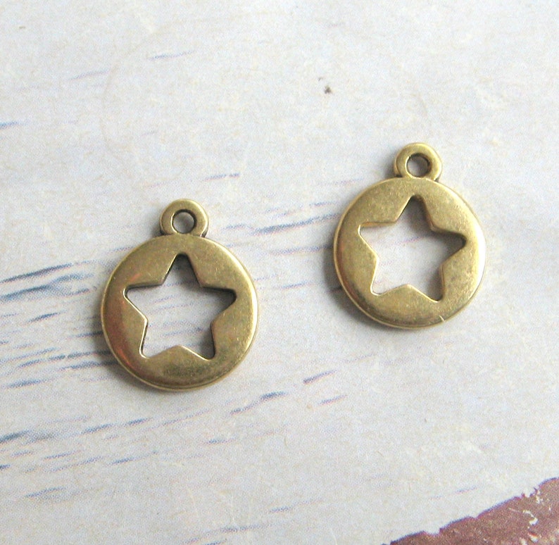 May include: Two gold-toned metal charms in the shape of a circle with a star cut out in the center.