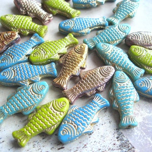 Könnte beinhalten: Eine Sammlung bunter Glasfischperlen mit goldenen Akzenten. Die Perlen sind in Blautönen, Grün- und Goldtönen gehalten. Sie eignen sich perfekt für die Schmuckherstellung oder andere Bastelprojekte.