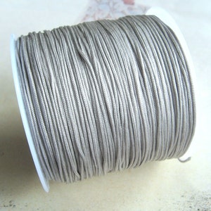 Könnte beinhalten: Eine Spule mit silbergrauem gewachstem Kordel, perfekt für die Schmuckherstellung, Makramee oder Basteln.