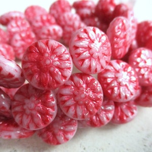 Könnte beinhalten: Eine Ansammlung roter und weißer Bonbons. Die Bonbons sind rund mit einem floralen Muster, das in die Oberfläche geschnitzt ist. Die Bonbons sind eine Mischung aus hellrosa und rot, wobei das Rot das florale Muster hervorhebt.
