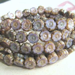 Può includere: Una collana di perline di vetro a forma di fiore, di colore marrone e viola. Le perline sono piccole e hanno un design a fiore in rilievo.