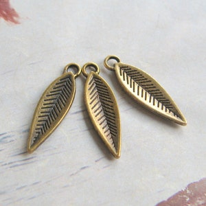 K&ouml;nnte beinhalten: Drei antike goldene Blatt-Anh&auml;nger mit strukturiertem Design. Die Bl&auml;tter sind etwa 2,5 cm lang und haben oben ein Loch zum Anbringen an Schmuck oder andere Bastelarbeiten.