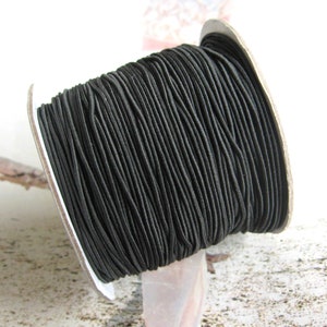 Peut inclure: Une bobine de cordon élastique noir, enroulé serré sur un noyau en carton. Le cordon est fin et flexible, parfait pour l'artisanat et la fabrication de bijoux.