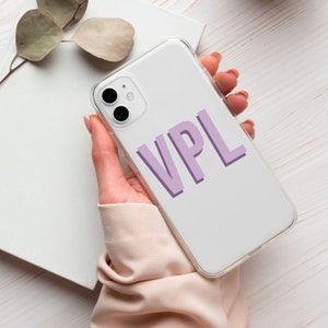 May include: A white phone case with a clear back and a purple 'VPL' design. The case is being held in a hand.