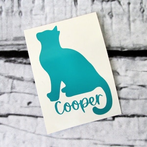 May include: Teal blue cat silhouette decal with the name "Cooper" written underneath.