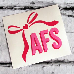 May include: Pink vinyl decal with a pink bow and a heart in the center. The decal says "AFS" in large pink letters.