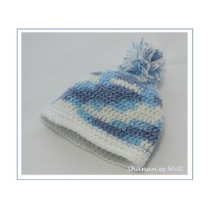 May include: A white and blue striped crocheted hat with a white pom-pom on top. The hat has a white crocheted brim.