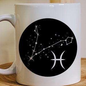 May include: White ceramic mug with a black circle design featuring a white constellation of the Pisces zodiac sign and the Pisces symbol.