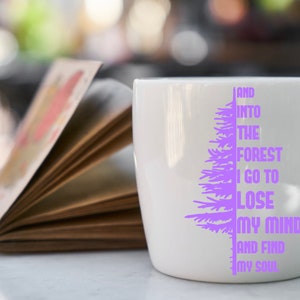Puede incluir: Taza de cer&aacute;mica blanca con un dise&ntilde;o de &aacute;rbol morado y el texto "And into the forest I go to lose my mind and find my soul".