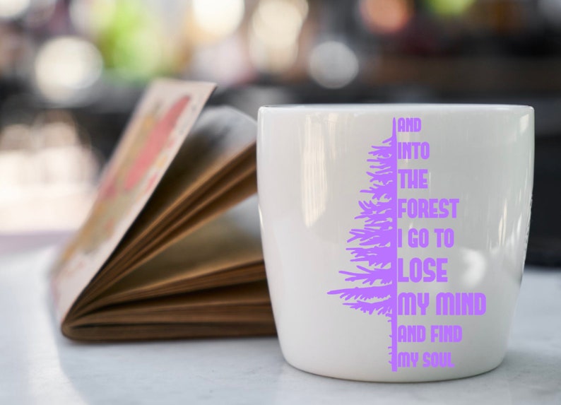 Puede incluir: Taza de cer&aacute;mica blanca con un dise&ntilde;o de &aacute;rbol morado y el texto "And into the forest I go to lose my mind and find my soul".