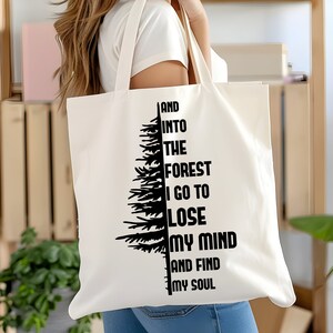 Pu&ograve; includere: Borsa tote in tela bianca con testo nero e una silhouette di albero. Il testo dice "And into the forest I go to lose my mind and find my soul."