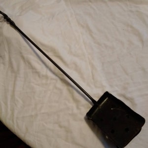 May include: A black metal fireplace tool with a long, twisted handle and a rectangular scoop at the end.