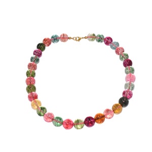 Può includere: Una collana di pietre preziose multicolori con perline rotonde in tonalità di rosa, verde e marrone. La collana è realizzata con pietre preziose naturali e ha una chiusura dorata.