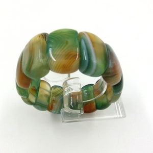 May include: A green, brown, and white agate stone bracelet with a polished finish. The bracelet is made of multiple round beads that are strung together.