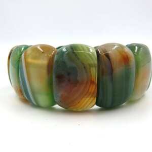 May include: A green, brown, and white agate stone bracelet with oval-shaped beads.