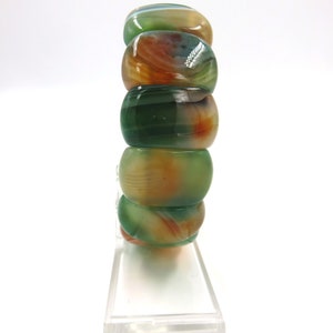 May include: A stack of green, orange, and white agate beads. The beads are round and have a polished finish.