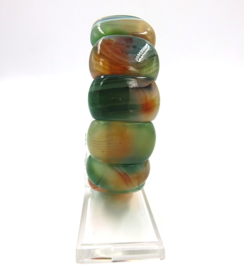May include: A stack of green, orange, and white agate beads. The beads are round and have a polished finish.