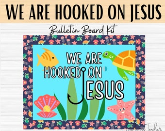 May include: A blue bulletin board with a sea-themed design. The text "We are hooked on Jesus" is written in white letters. There are images of a fish, a turtle, a starfish, and a hook.