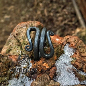 May include: A black metal ring with a unique, twisted design. The ring is handcrafted and has a rustic, antique look.