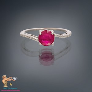 May include: A silver ring featuring a red ruby gemstone and small diamonds on the band.
