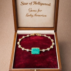 May include: A gold-toned bracelet with a rectangular, turquoise-colored center stone and surrounding clear stones, displayed in a wooden box with the text "Star of Hollywood Gems for Lady America" on the inside lid, set against a red velvet lining.
