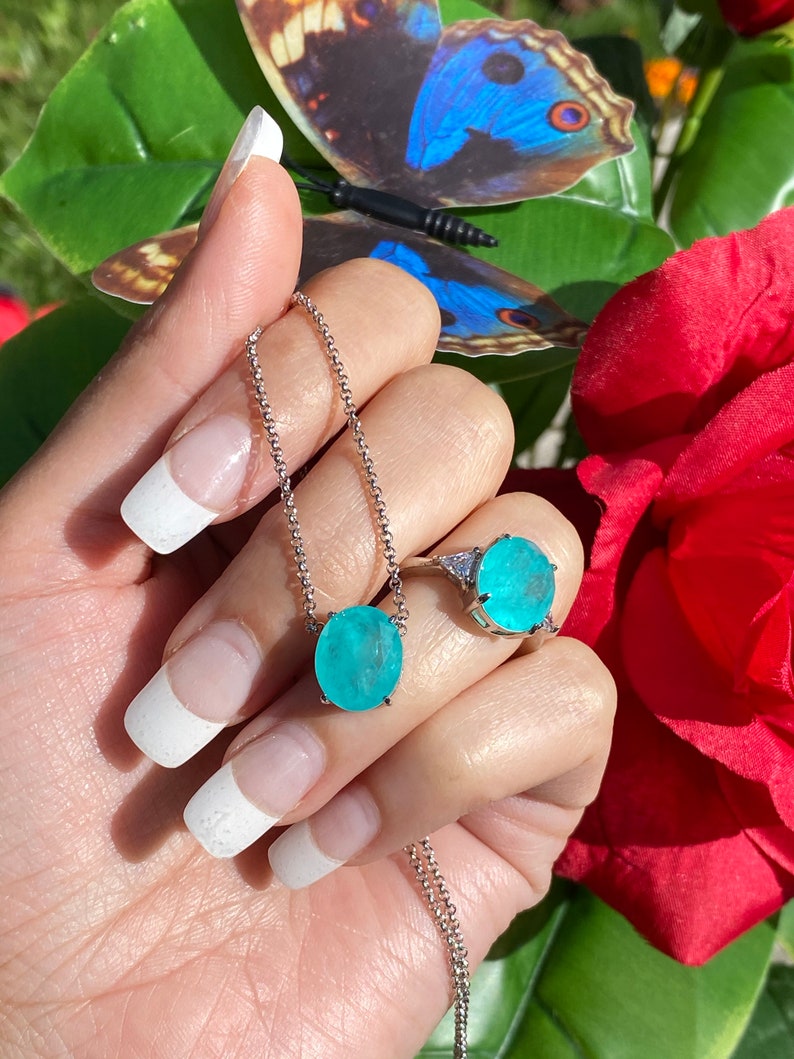 May include: A silver necklace and ring set featuring a turquoise gemstone. The necklace has a delicate chain and a round pendant with a turquoise stone. The ring has a similar turquoise stone and a silver band.