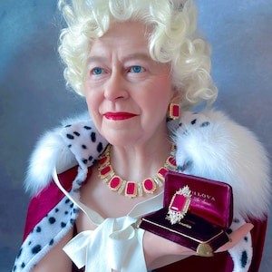 May include: A woman wearing a crown and a red and white fur-trimmed robe holds a red velvet box with a large ruby ring inside. The ring is surrounded by smaller diamonds.