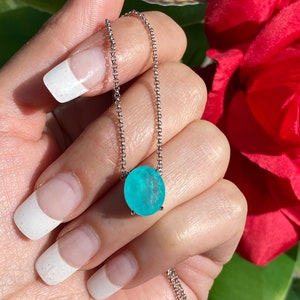 May include: A silver chain necklace with a light blue oval-shaped gemstone pendant.
