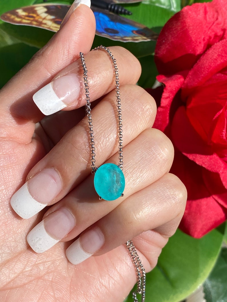 May include: A silver chain necklace with a light blue oval-shaped gemstone pendant.