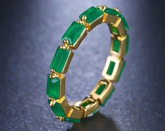 May include: A gold ring with a row of emerald green rectangular stones.