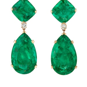 May include: A pair of gold earrings with emerald and diamond accents. The earrings feature a square emerald stone at the top and a pear-shaped emerald stone hanging below.