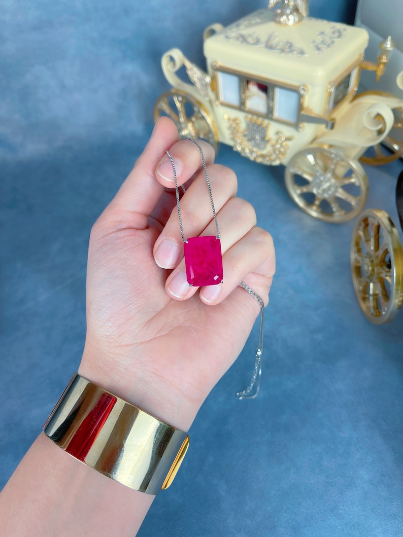 May include: A silver chain necklace with a large, rectangular, bright pink gemstone pendant.