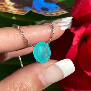 May include: A silver chain necklace with a light blue oval gemstone pendant.