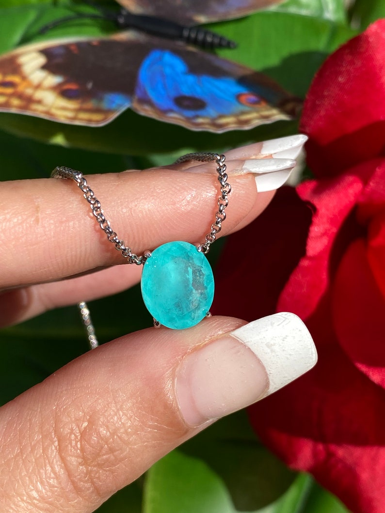 May include: A silver chain necklace with a light blue oval gemstone pendant.