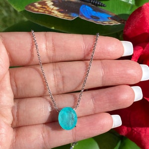 May include: A silver chain necklace with a light blue oval gemstone pendant.